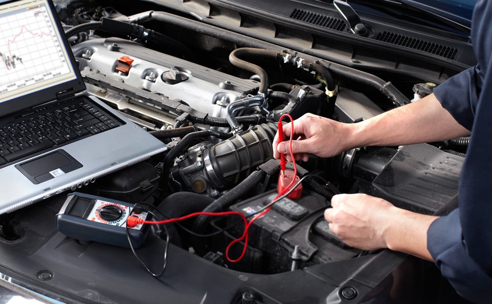 Up-close image of a service technician working on a car battery - Minocqua Chevrolet in MINOCQUA WI